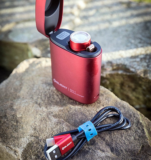 picture of an Olight torch with charger battery on a rock