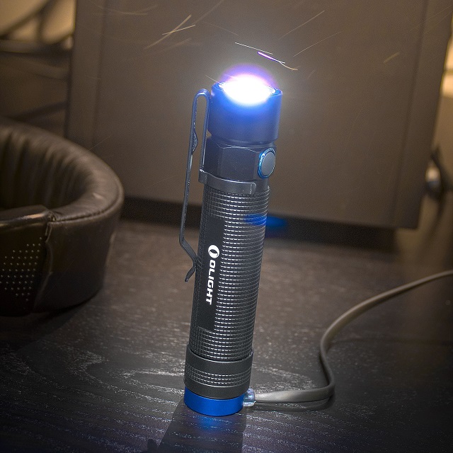 picture of an Olight flashlight connected to a charger on the table