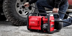 Man using a portable red air compressor to inflate a vehicle tire.